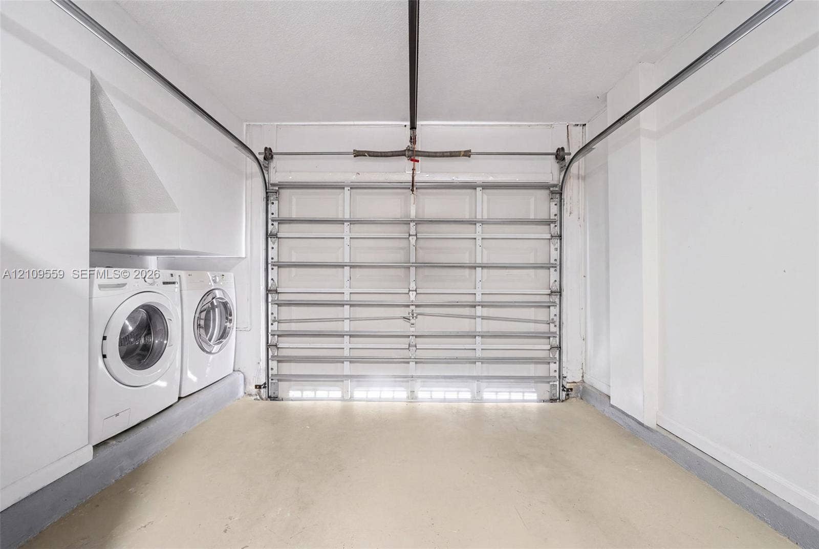 10217 NW 56th Street, Doral, FL 33178 Garage featuring an overhead sectional door, concrete flooring, and built-in laundry hookups