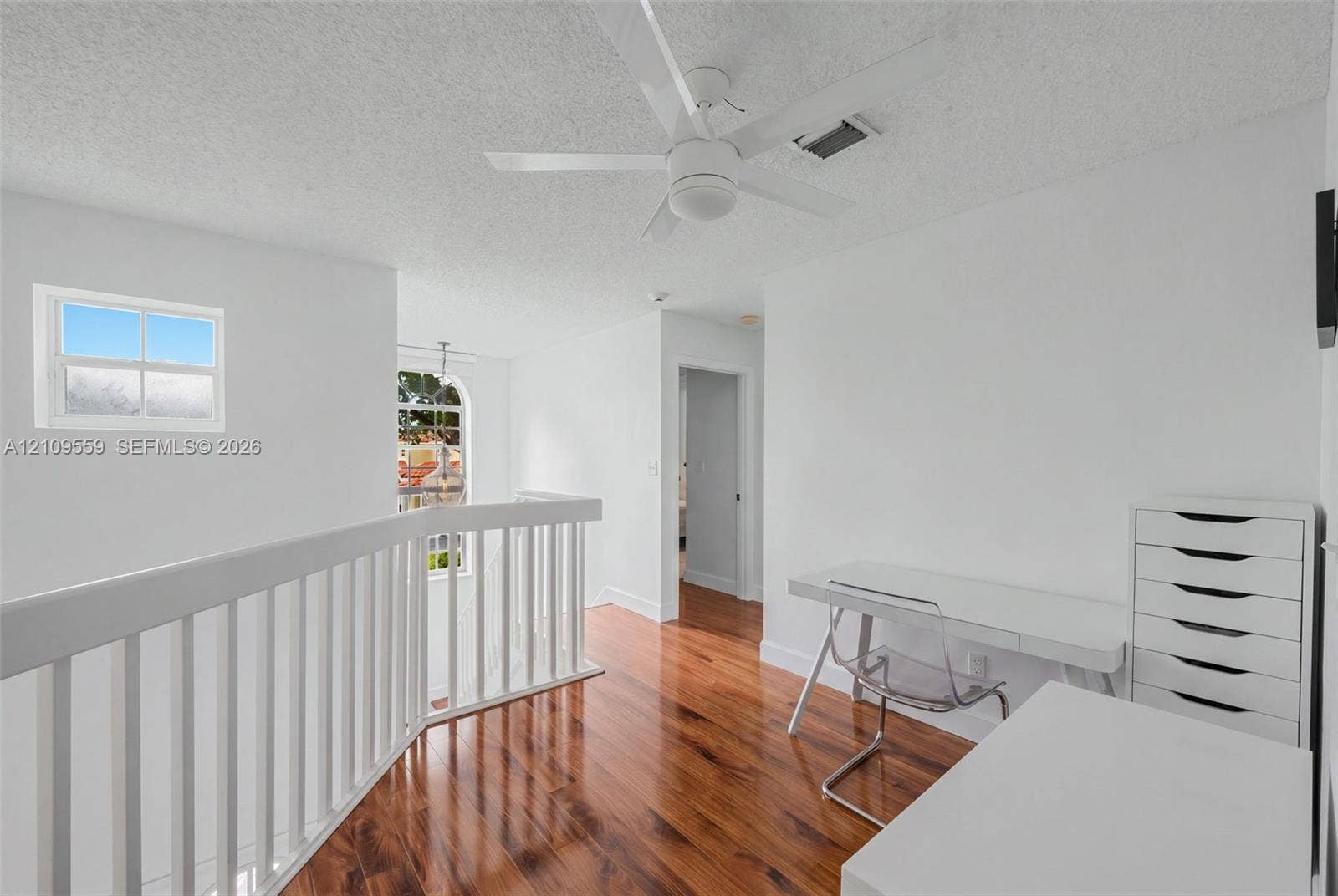 10217 NW 56th Street, Doral, FL 33178 Wood-finish flooring, white wooden balustrade, arched multi-pane window, and white ceiling fan