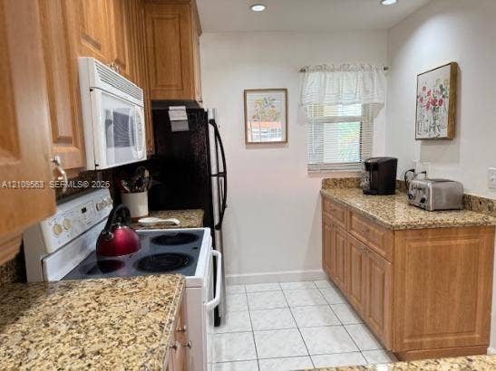 Kitchen featuring wood cabinetry, stone countertops, tiled flooring, and recessed ceiling lighting