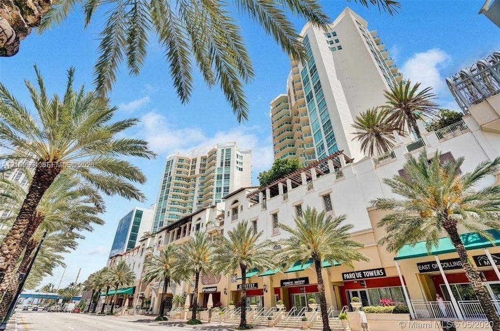 200 Sunny Isles Boulevard, #2-604, Sunny Isles Beach, Sunny Isles Beach, FL 33160 High-rise architectural exterior featuring multi-level balconies, ground-level retail storefronts with canvas awnings, and prominent palm tree landscaping