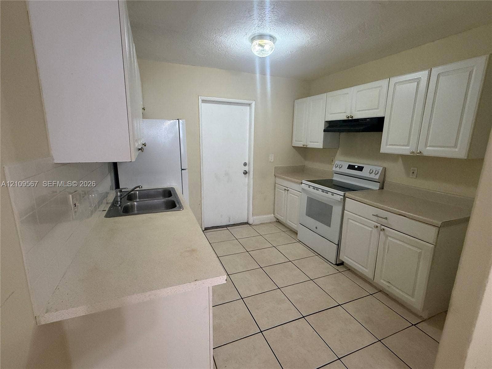 1132 NE 5th Avenue, #1, Fort Lauderdale, Fort Lauderdale, FL 33304 Kitchen featuring white cabinetry, solid surface countertops, stainless steel dual-basin sink, tile flooring, and integrated range hood