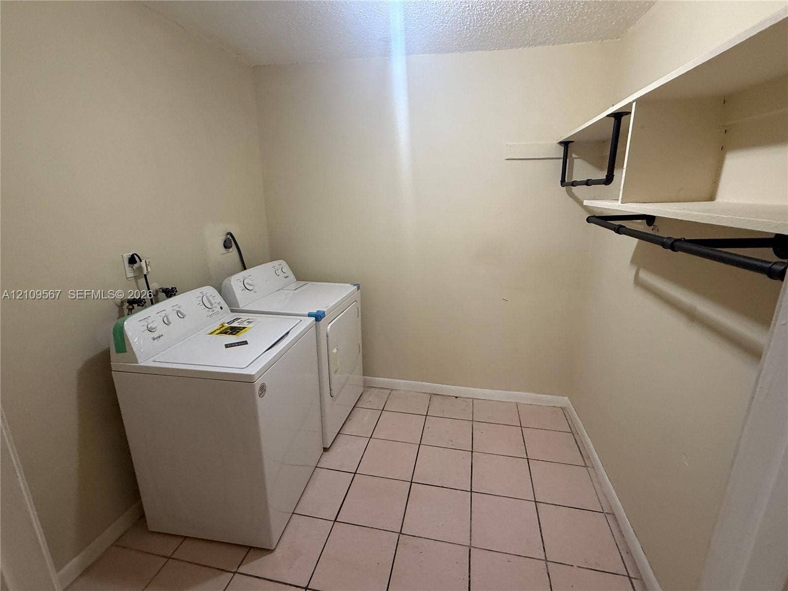 1132 NE 5th Avenue, #1, Fort Lauderdale, Fort Lauderdale, FL 33304 Laundry area featuring white appliances, tile flooring, and built-in shelving with an industrial-style pipe clothing rack