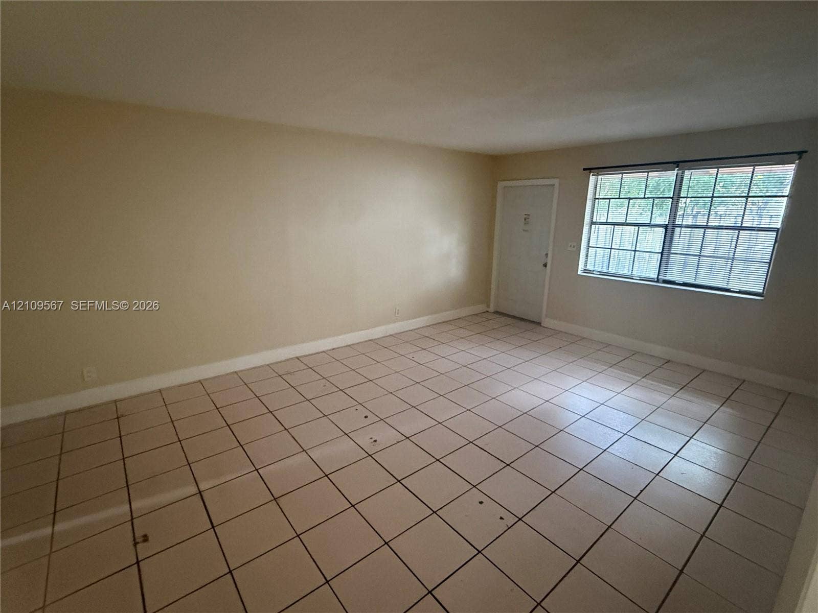 1132 NE 5th Avenue, #1, Fort Lauderdale, Fort Lauderdale, FL 33304 Neutral-toned interior space featuring light-colored tile flooring, smooth walls, and a window with a colonial grille pattern