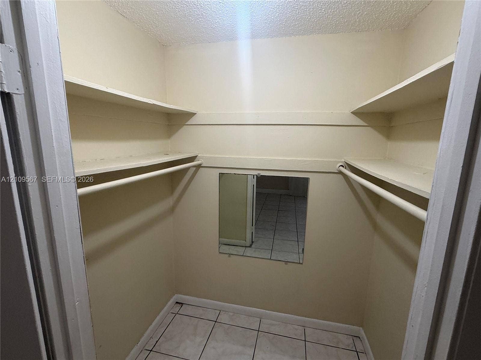 1132 NE 5th Avenue, #1, Fort Lauderdale, Fort Lauderdale, FL 33304 Walk-in storage space featuring multi-level shelving, integrated hanging rods, square tile flooring, and a wall-mounted mirror