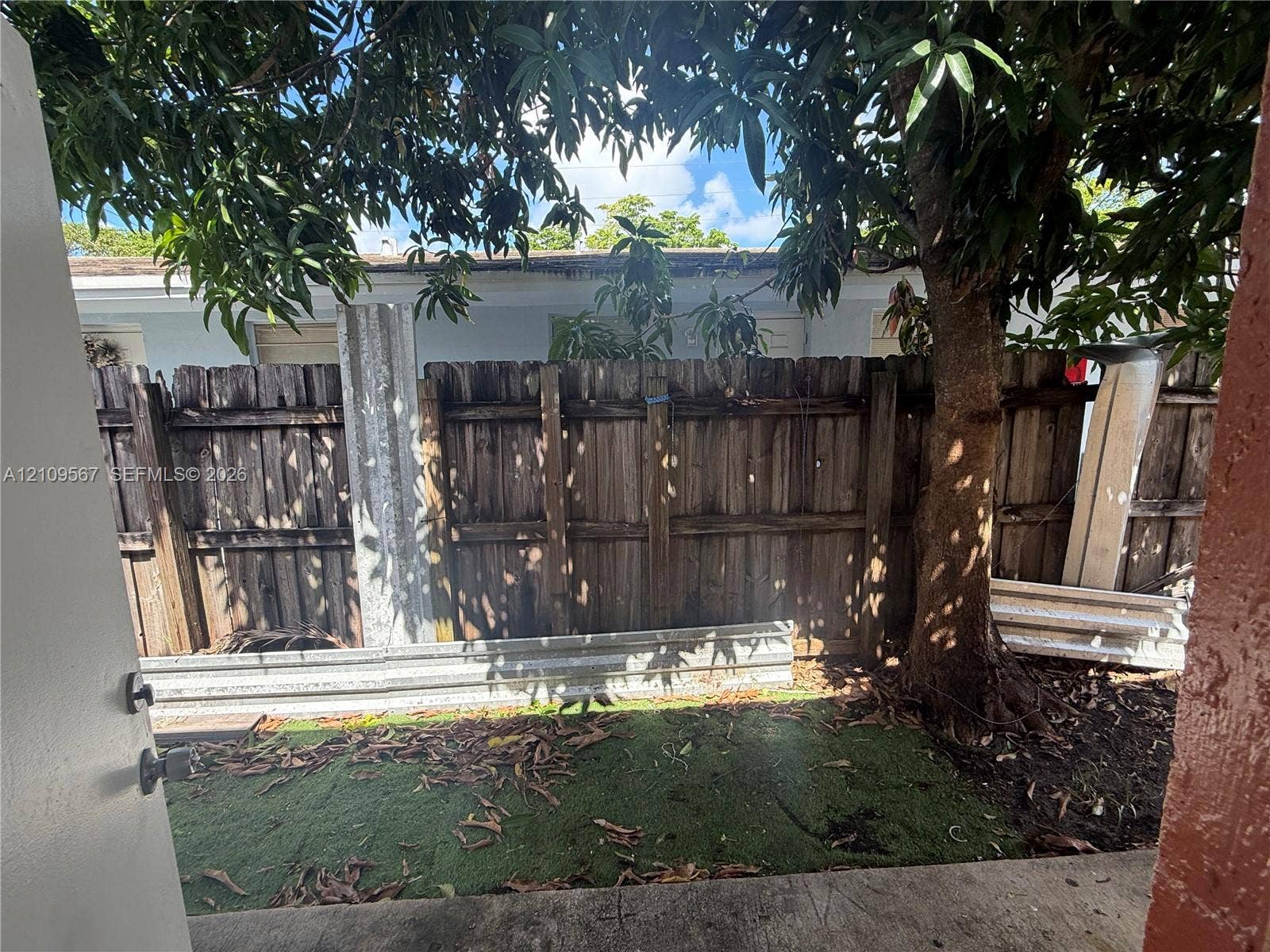1132 NE 5th Avenue, #1, Fort Lauderdale, Fort Lauderdale, FL 33304 Outdoor area featuring a concrete patio, synthetic turf lawn, mature tree, and wood-panel privacy fencing