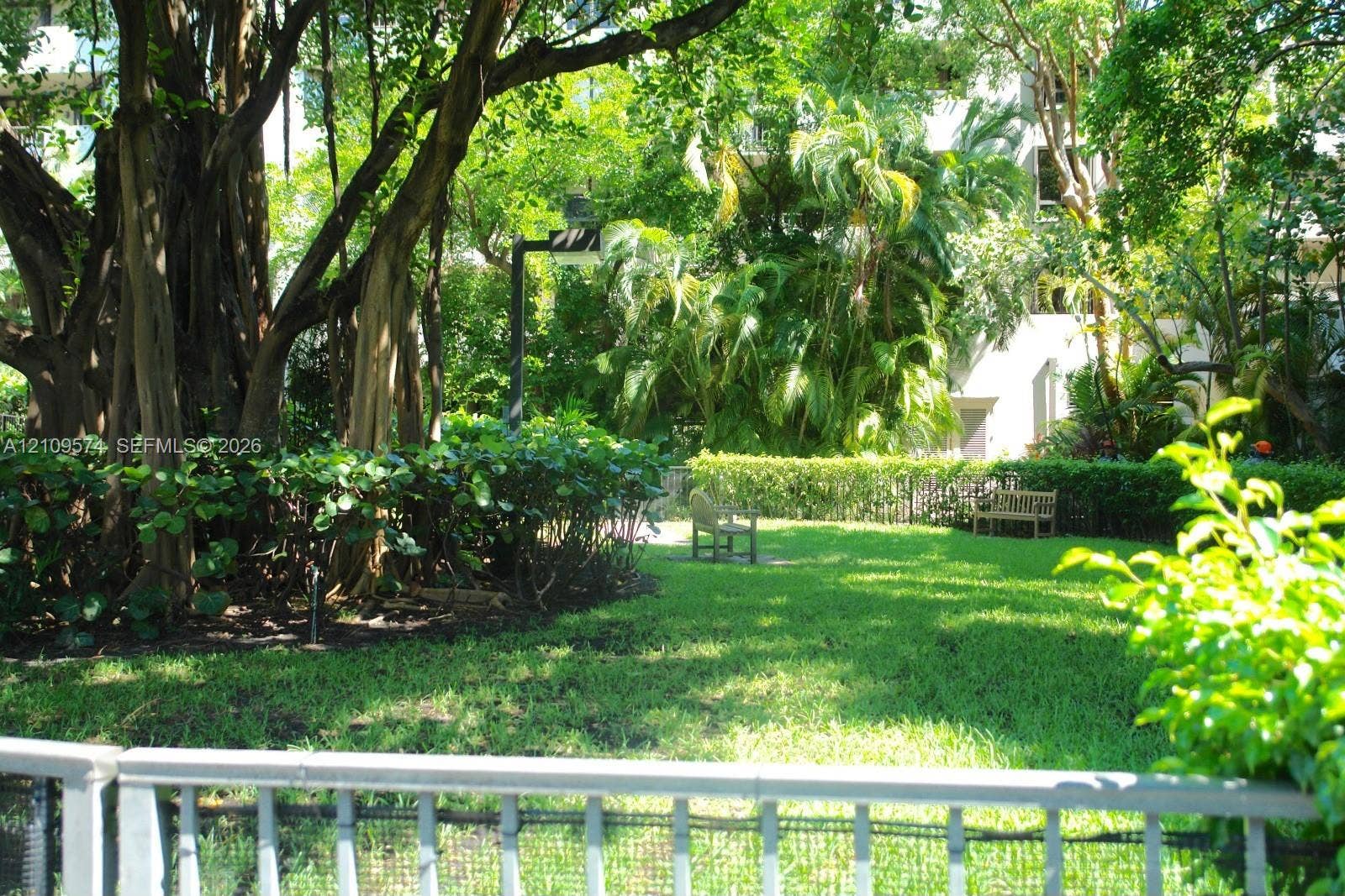 Lush outdoor grounds featuring mature trees, manicured hedges, open lawn space, and exterior lighting fixtures