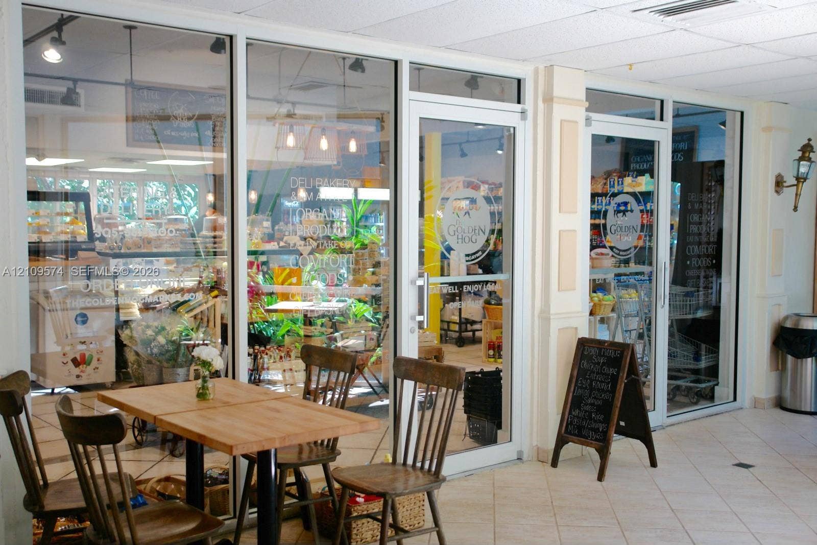 Commercial storefront featuring expansive glass panels, white aluminum framing, neutral ceramic tile flooring, and wall-mounted exterior-style lighting