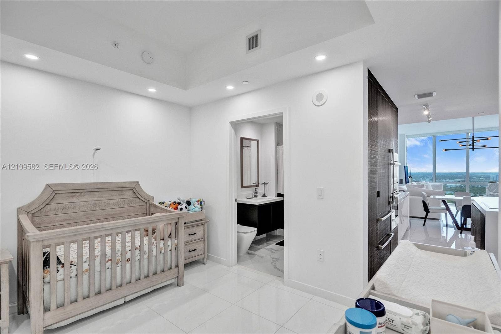Interior room featuring high ceilings with recessed lighting, large-format tile flooring, and an attached bathroom with a modern vanity