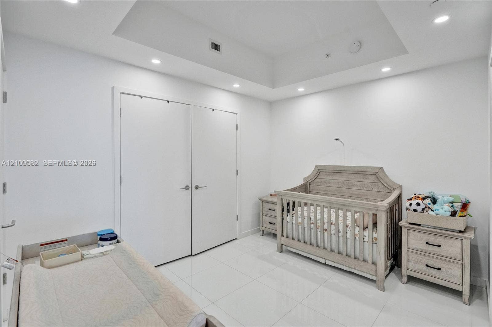Interior space featuring high-gloss tile flooring, a recessed tray ceiling, integrated recessed lighting, and a double-door reach-in closet