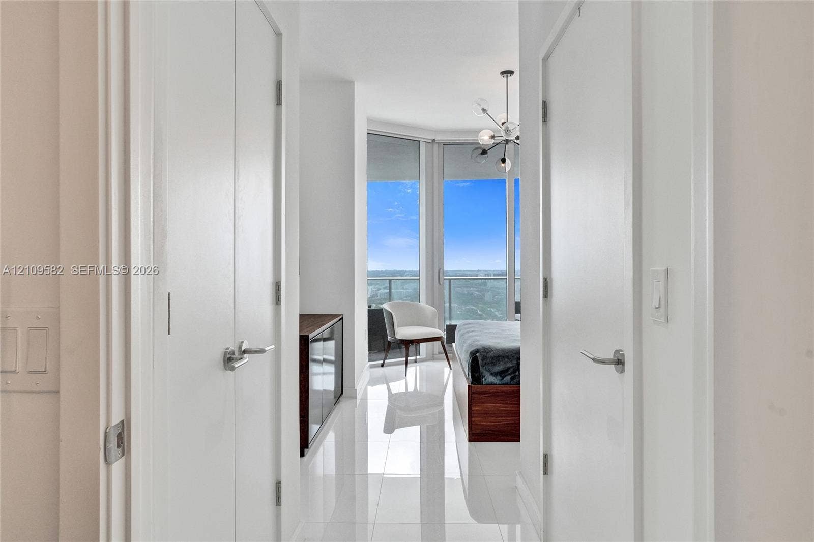 Floor-to-ceiling windows, polished tile flooring, multi-arm chandelier, and double-closet configuration