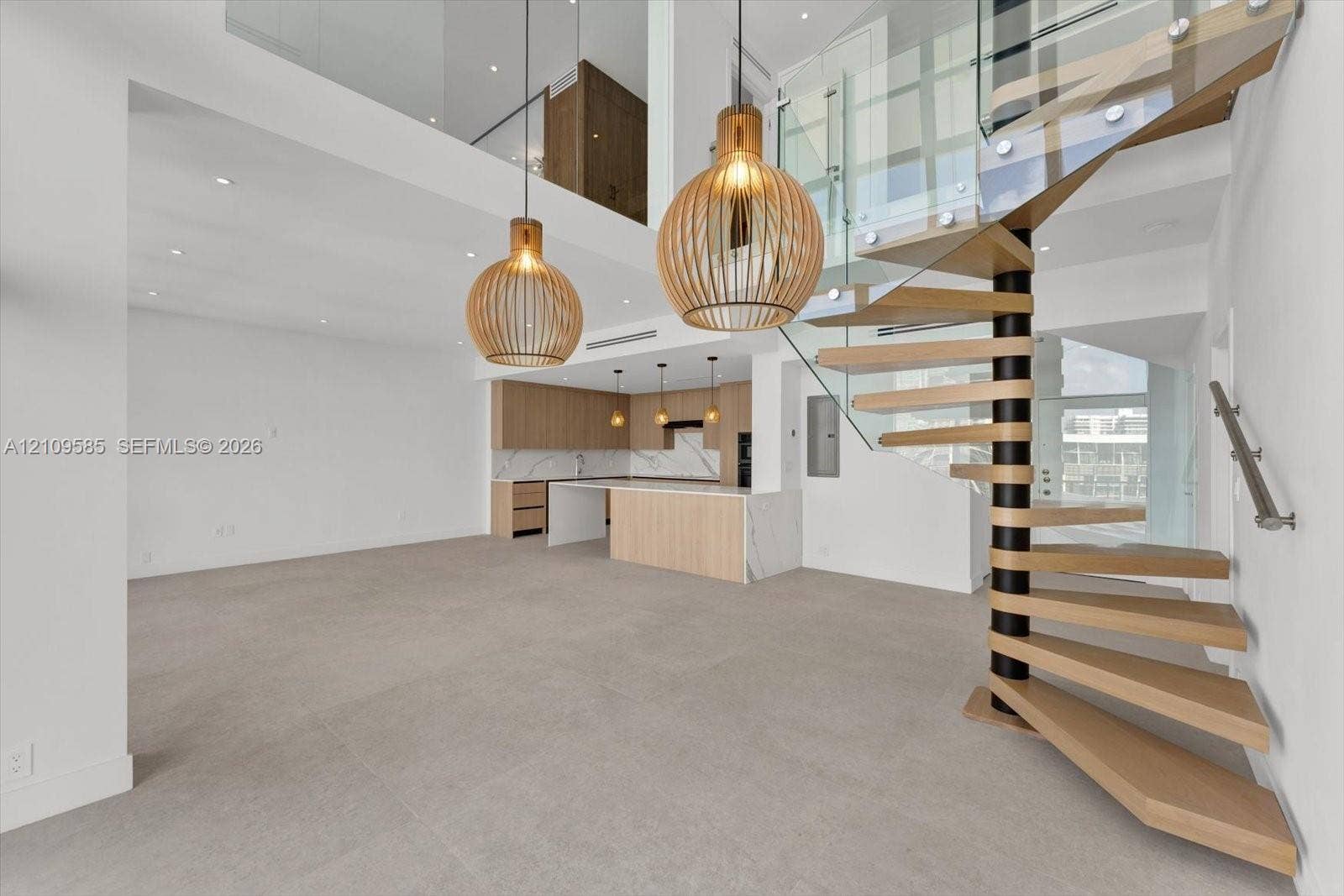 1865 Brickell Avenue, #APHVII, Miami, FL 33129 Spiral staircase featuring wooden treads and a glass railing, complemented by two large cage-style pendant lights, light wood-finish cabinetry, stone countertops, and tile flooring