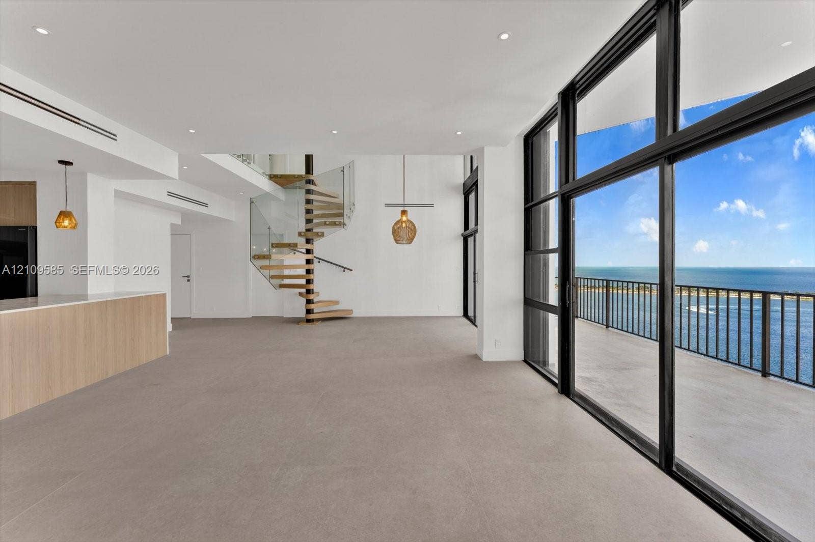 1865 Brickell Avenue, #APHVII, Miami, FL 33129 Floor-to-ceiling glass panel walls, spiral staircase with glass railing, recessed lighting, wood-finish kitchen island, and private balcony