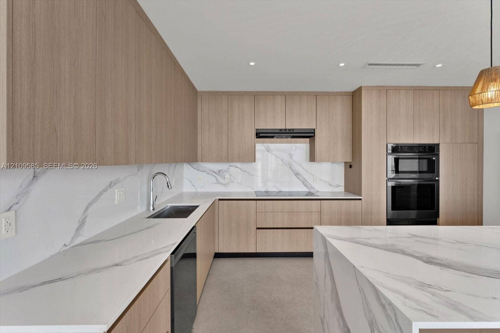 1865 Brickell Avenue, #APHVII, Miami, FL 33129 Kitchen featuring flat-panel wood-finish cabinetry, waterfall-edge stone countertops, matching stone slab backsplash, stainless steel built-in double oven, and recessed lighting
