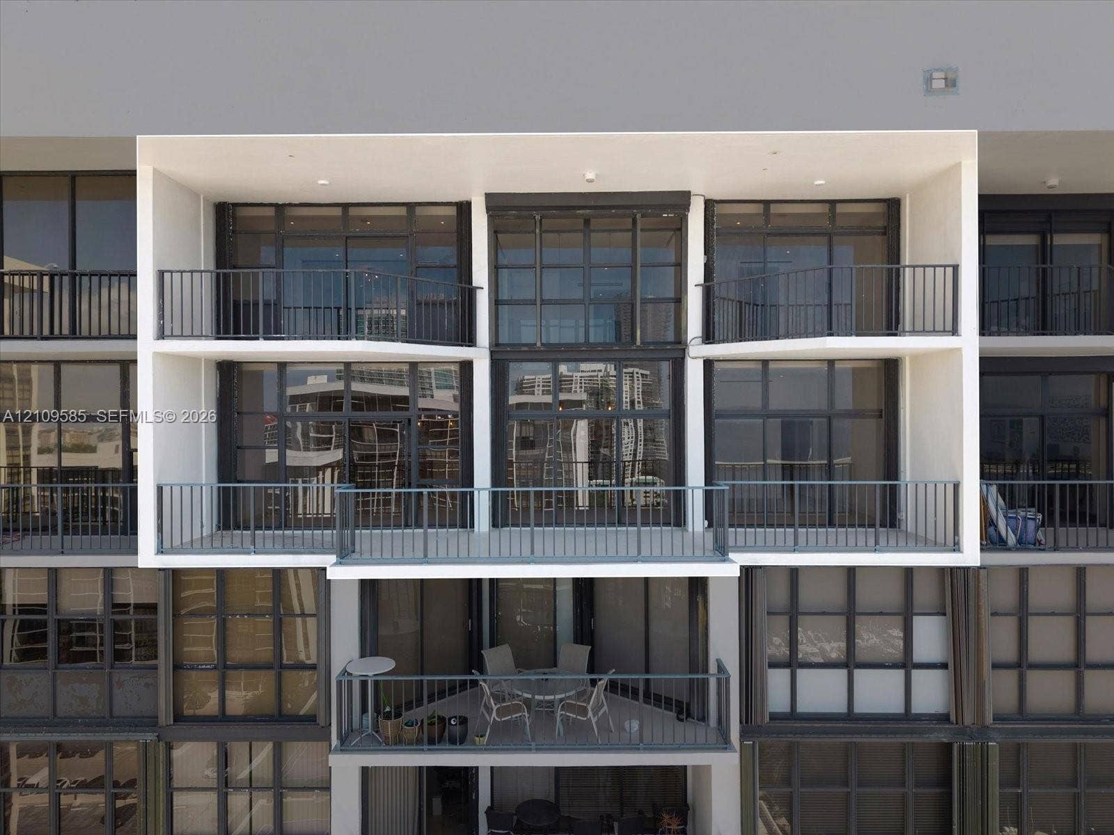 1865 Brickell Avenue, #APHVII, Miami, FL 33129 Contemporary building facade featuring multi-level open-air balconies, dark-framed floor-to-ceiling glass windows, and metal railings