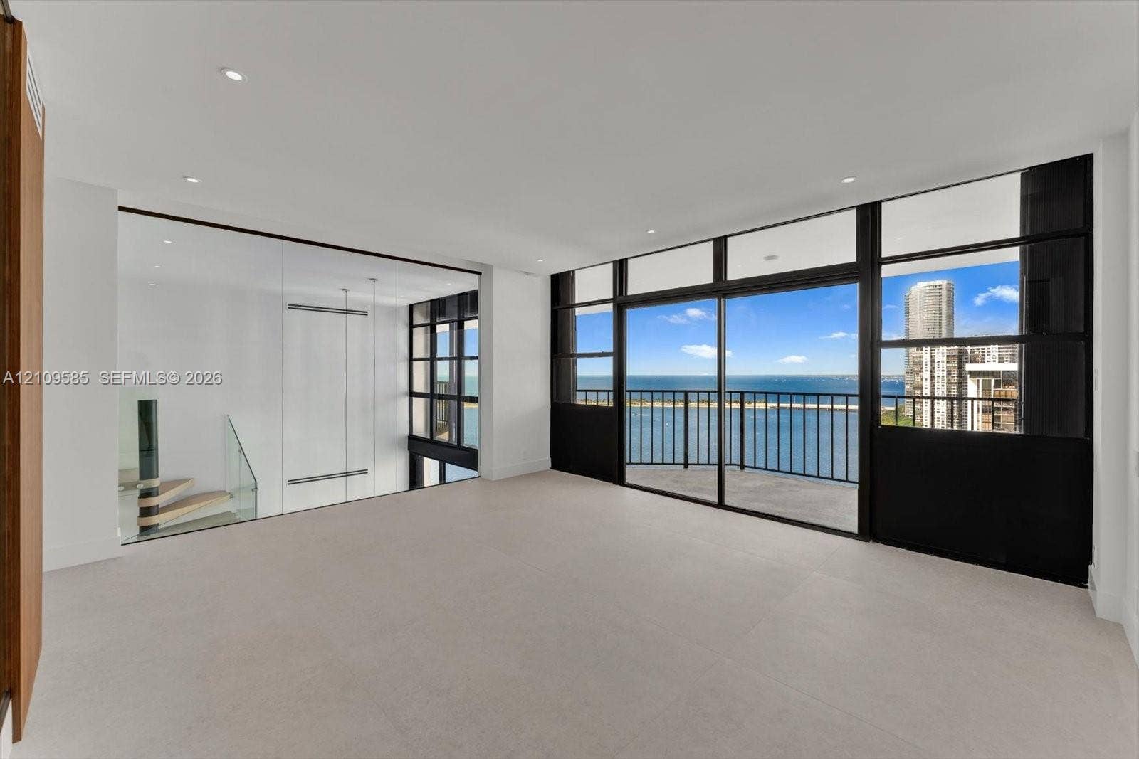1865 Brickell Avenue, #APHVII, Miami, FL 33129 Primary Suite with exterior balcony, stone-finish flooring, glass-paneled interior partition, and staircase with glass railing