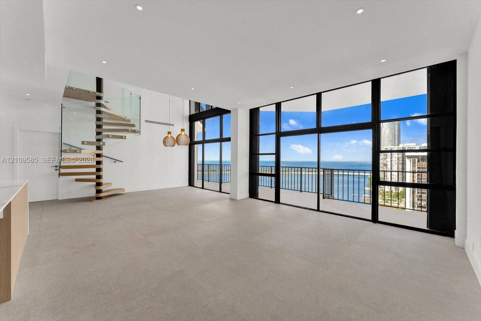 1865 Brickell Avenue, #APHVII, Miami, FL 33129 Open-concept interior featuring floor-to-ceiling windows, spiral staircase with glass railing, large-format tile flooring, and recessed lighting