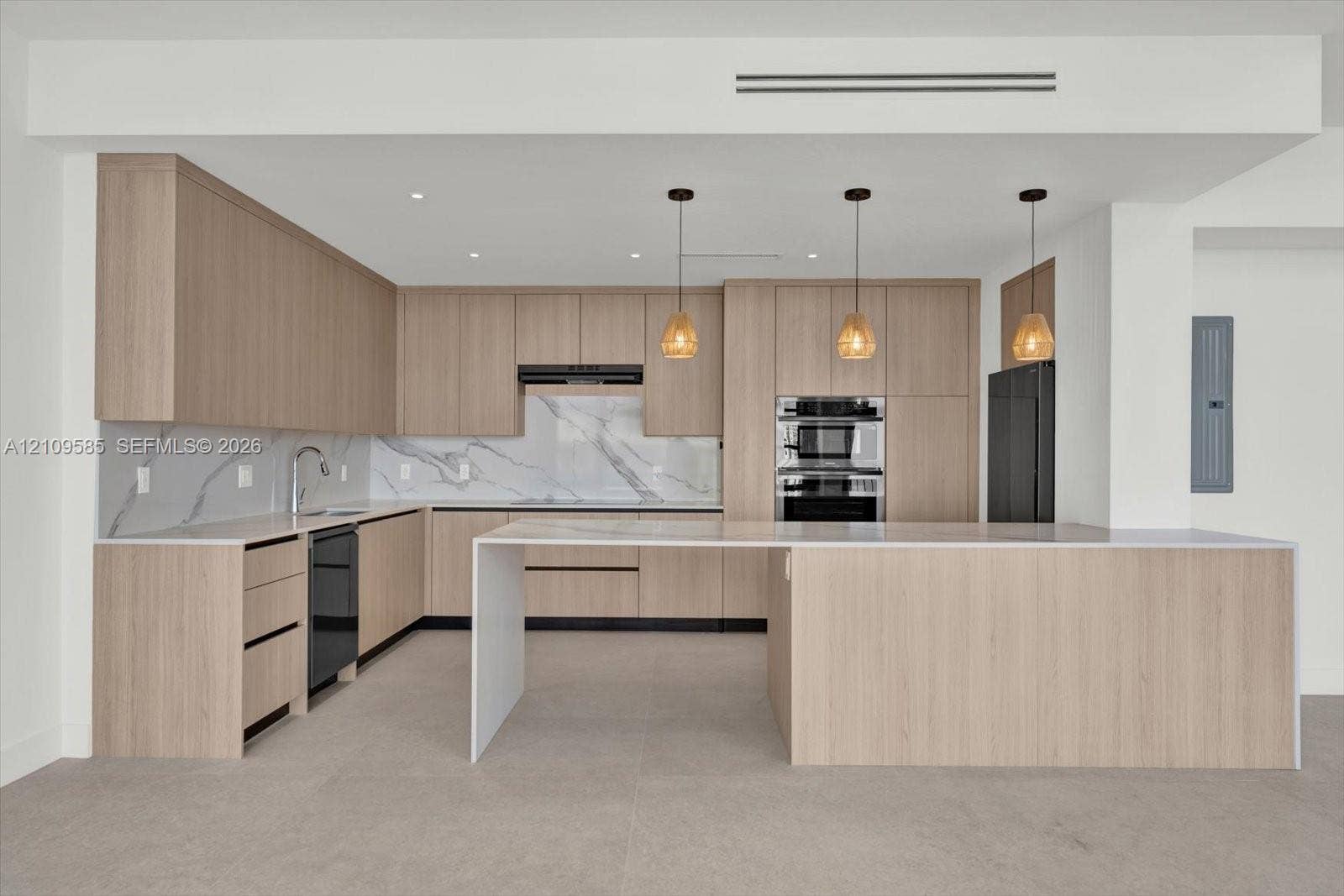 1865 Brickell Avenue, #APHVII, Miami, FL 33129 Kitchen featuring light wood-finish cabinetry, waterfall-edge island, stone-patterned backsplash, built-in double oven, and pendant lighting
