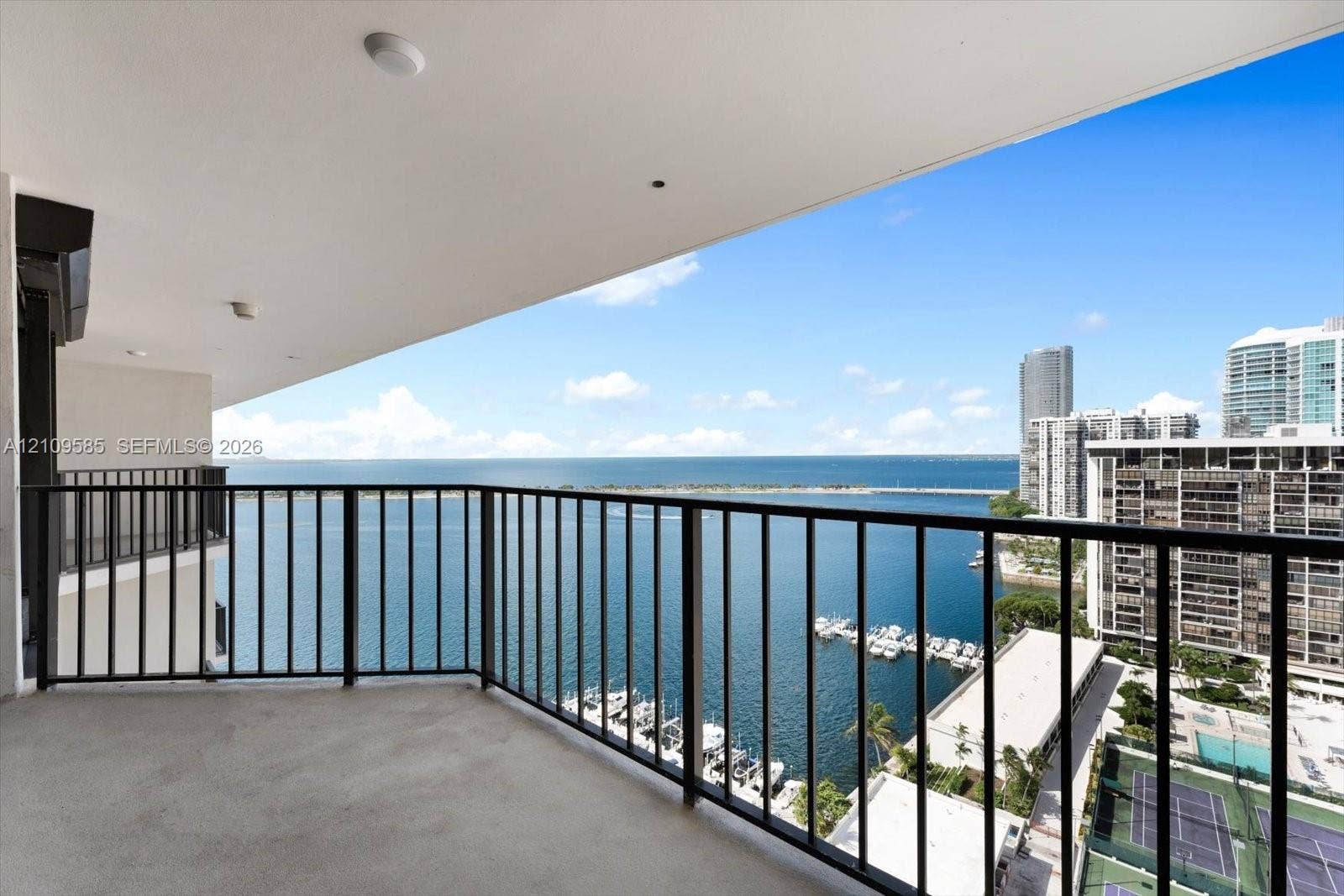 1865 Brickell Avenue, #APHVII, Miami, FL 33129 Covered balcony with black metal railing, concrete flooring, and water frontage