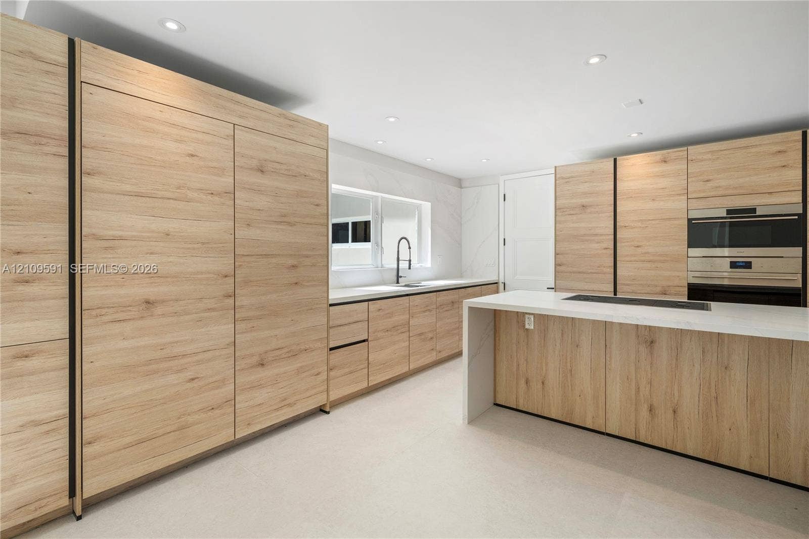 864 NE 91st Terrace, Miami Shores, FL 33138 Kitchen featuring wood-finish cabinetry, a waterfall-edge island with countertop, recessed lighting, a built-in wall oven, and a single-basin sink with a matte black faucet