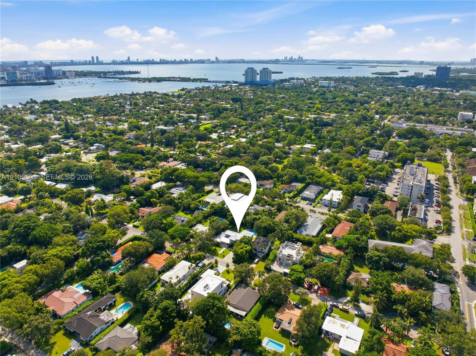 864 NE 91st Terrace, Miami Shores, FL 33138 Aerial perspective of a residential lot situated within a heavily forested landscape featuring proximity to coastal waterways and an urban skyline