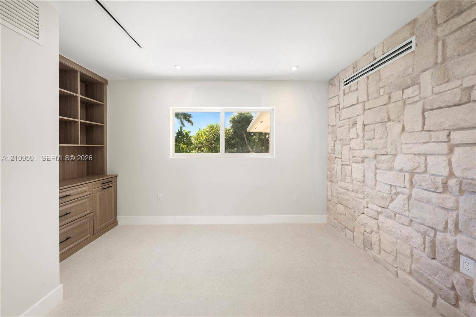 864 NE 91st Terrace, Miami Shores, FL 33138 Stone accent wall, built-in wooden cabinetry featuring drawers and shelving, and a horizontal window with exterior greenery