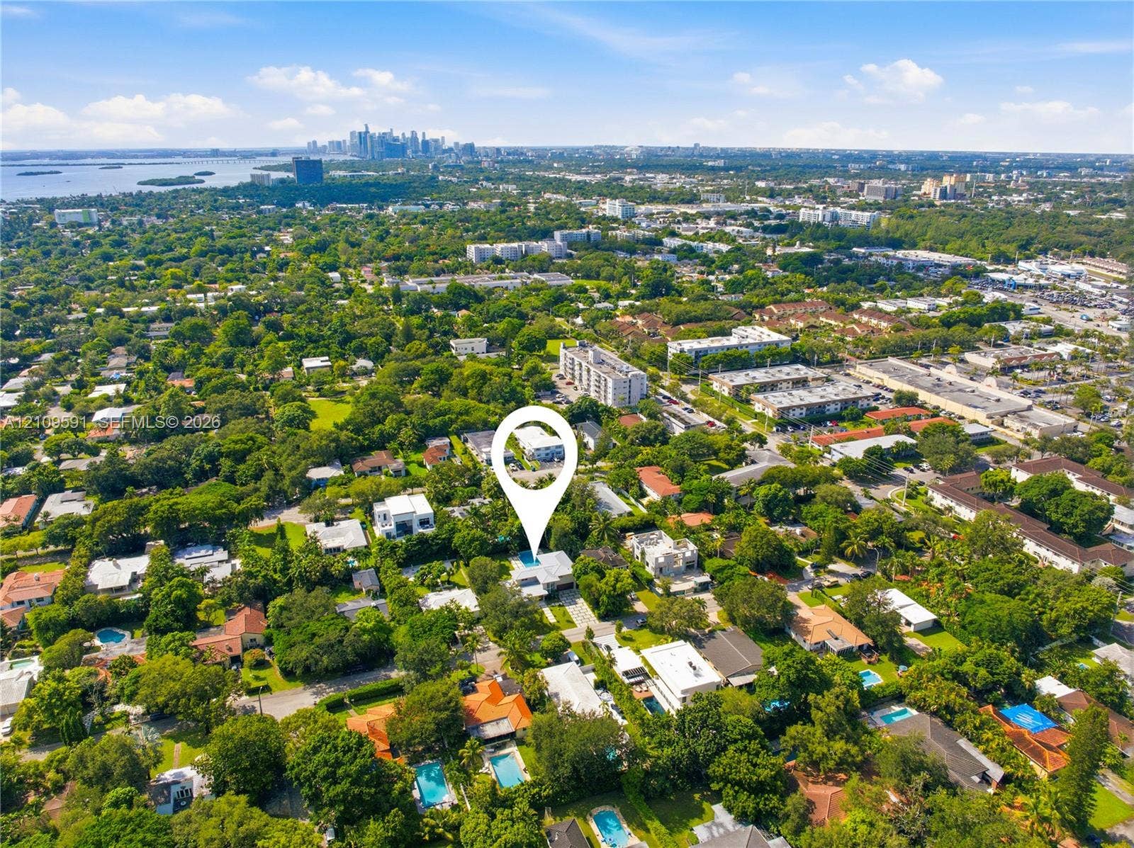 864 NE 91st Terrace, Miami Shores, FL 33138 Aerial perspective of a residential property featuring a private swimming pool, mature tree canopy, and proximity to metropolitan skyline and coastal waters
