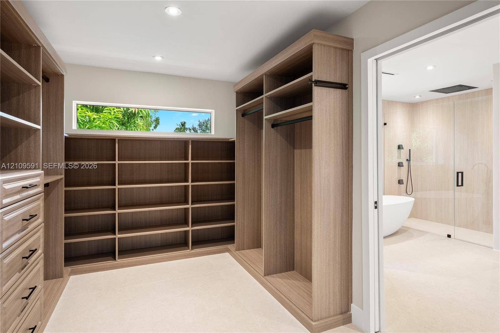 864 NE 91st Terrace, Miami Shores, FL 33138 Walk-in closet featuring floor-to-ceiling wood-finish cabinetry, built-in shelving, drawers with matte black hardware, and an elongated horizontal window