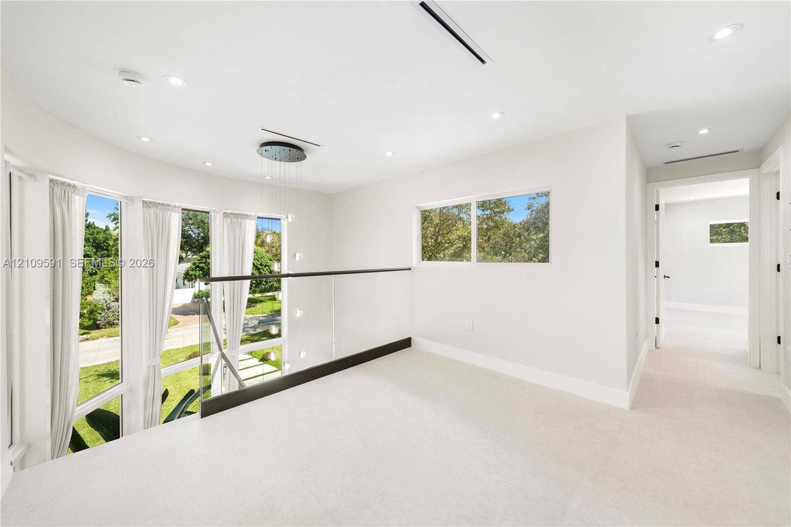 864 NE 91st Terrace, Miami Shores, FL 33138 Open-concept landing featuring floor-to-ceiling windows, glass paneled railing, recessed lighting, and a multi-tiered pendant fixture