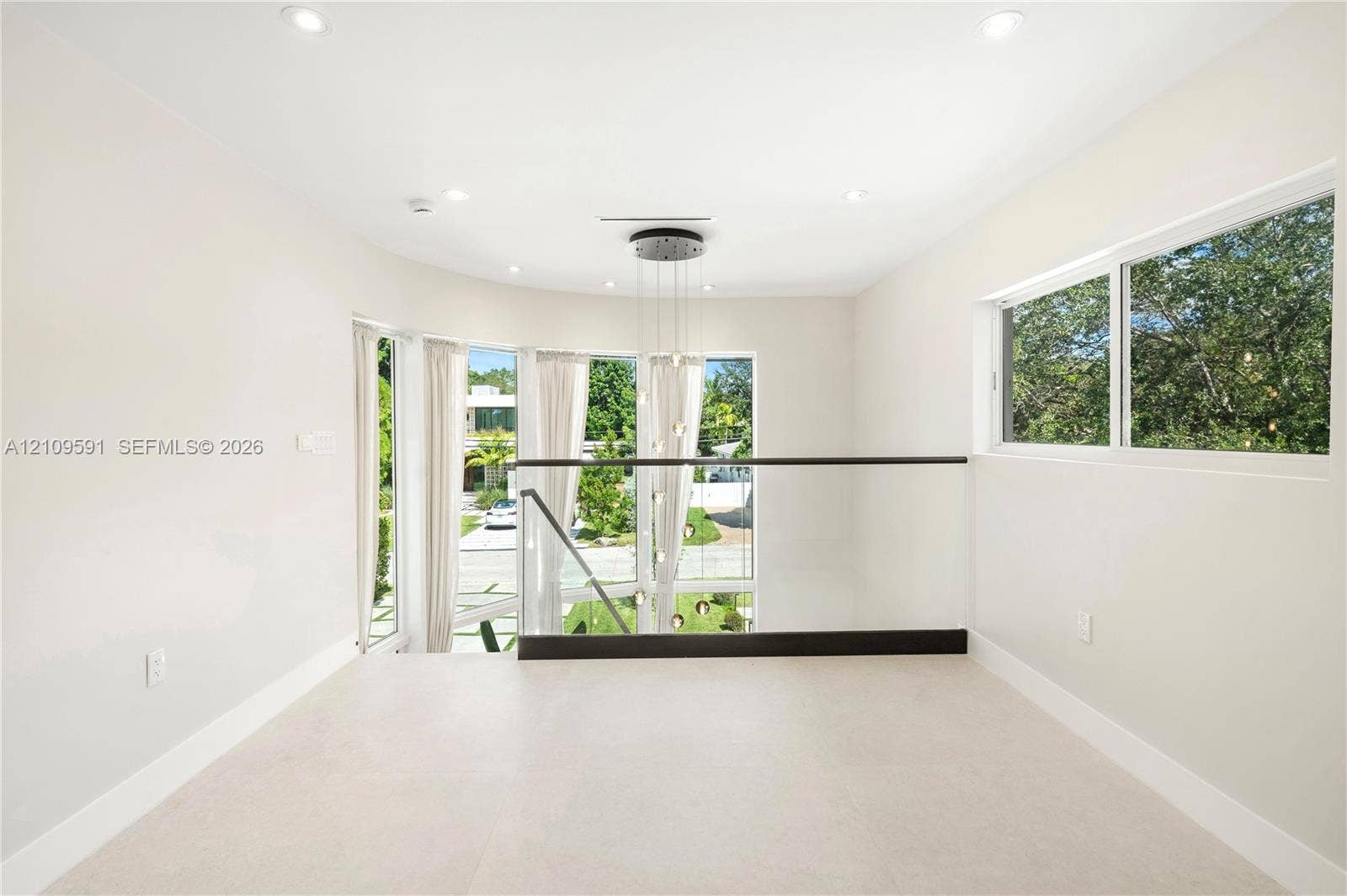 864 NE 91st Terrace, Miami Shores, FL 33138 Open-concept landing featuring recessed lighting, a multi-pendant light fixture, glass railings with dark-finished metal handrails, and expansive windows