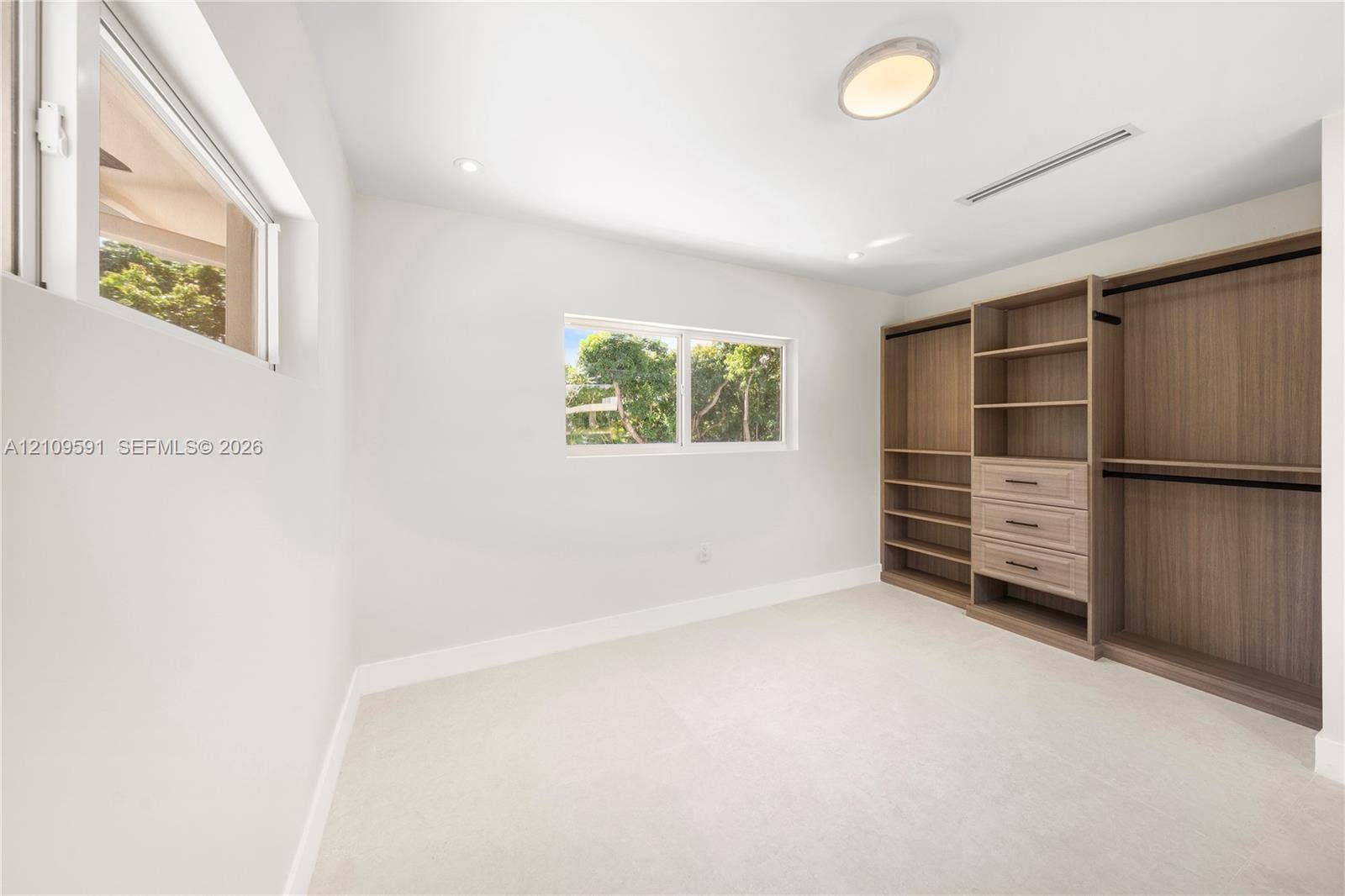 864 NE 91st Terrace, Miami Shores, FL 33138 Custom built-in wood-finish wardrobe system with integrated shelving and drawers, neutral carpeting, and multiple dual-pane windows