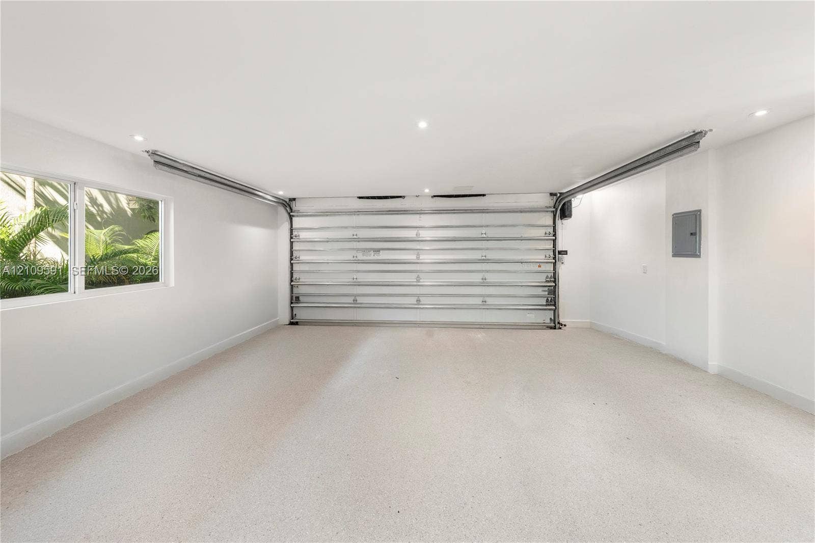 864 NE 91st Terrace, Miami Shores, FL 33138 Finished interior garage space featuring recessed lighting, a smooth-finish floor, a multi-panel overhead door, and a side window providing natural light