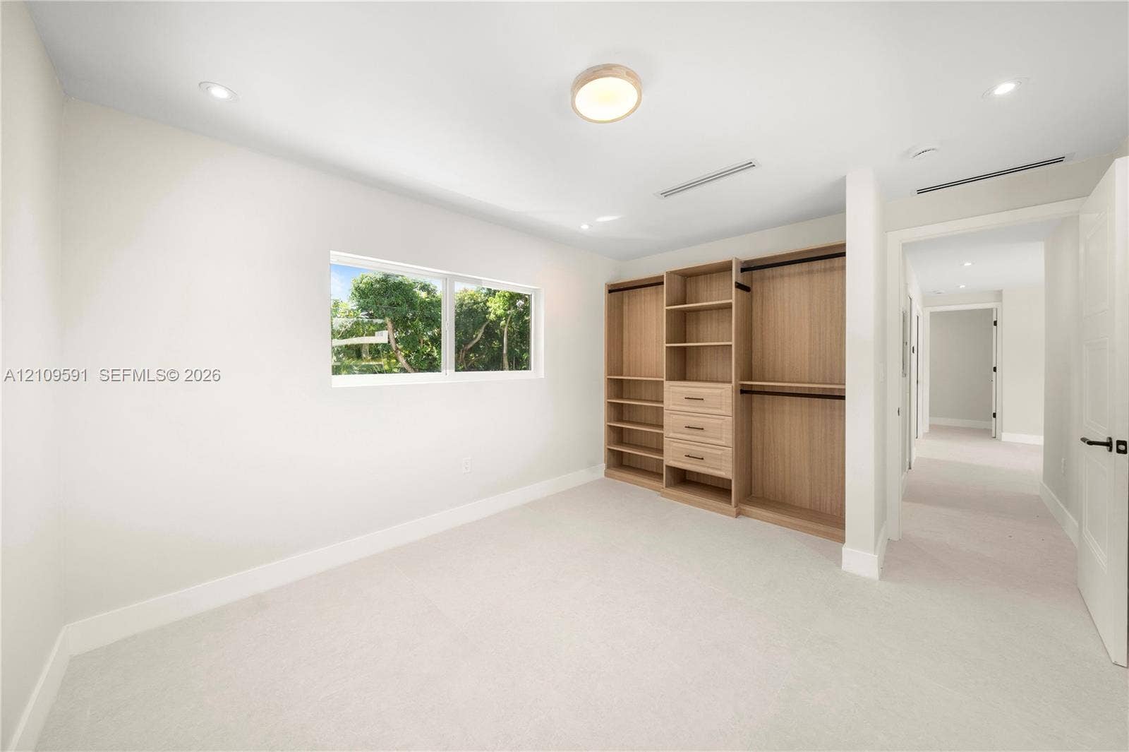 864 NE 91st Terrace, Miami Shores, FL 33138 Room featuring neutral wall-to-wall carpeting, recessed ceiling lighting, a rectangular window, and custom built-in cabinetry with integrated shelving and drawers