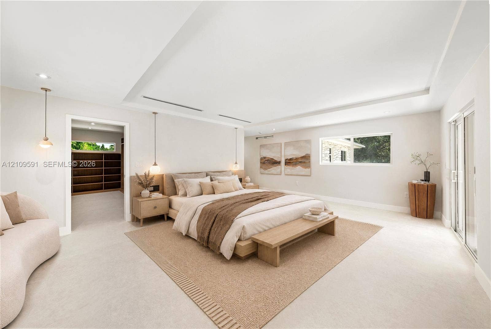 864 NE 91st Terrace, Miami Shores, FL 33138 Virtually Staged: Spacious room with recessed tray ceiling, neutral stone-finish flooring, built-in shelving, pendant lighting, and sliding glass doors