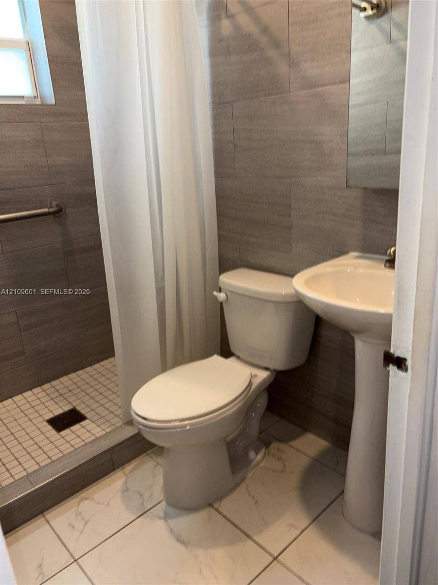 6320 Cleveland Street, Hollywood, Hollywood, FL 33024 Full-height horizontal tile wall finishes, walk-in shower with square mosaic flooring, pedestal sink, and large-format porcelain tile flooring