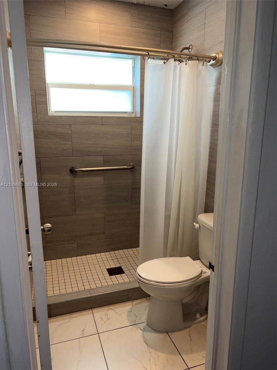 6320 Cleveland Street, Hollywood, Hollywood, FL 33024 Full-height wall tiling in wood-finish ceramic, walk-in shower with mosaic tile flooring, horizontal transom window, and white large-format floor tiling