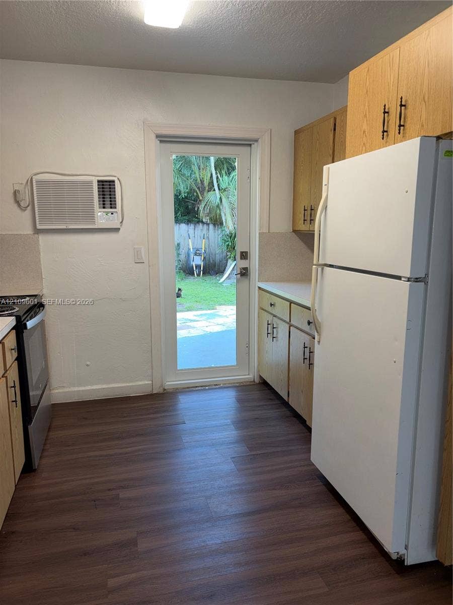 6320 Cleveland Street, Hollywood, Hollywood, FL 33024 Kitchen featuring wood-finish flooring, light-toned cabinetry with dark hardware, a full-size refrigerator, electric range, and a glass-paneled exterior door