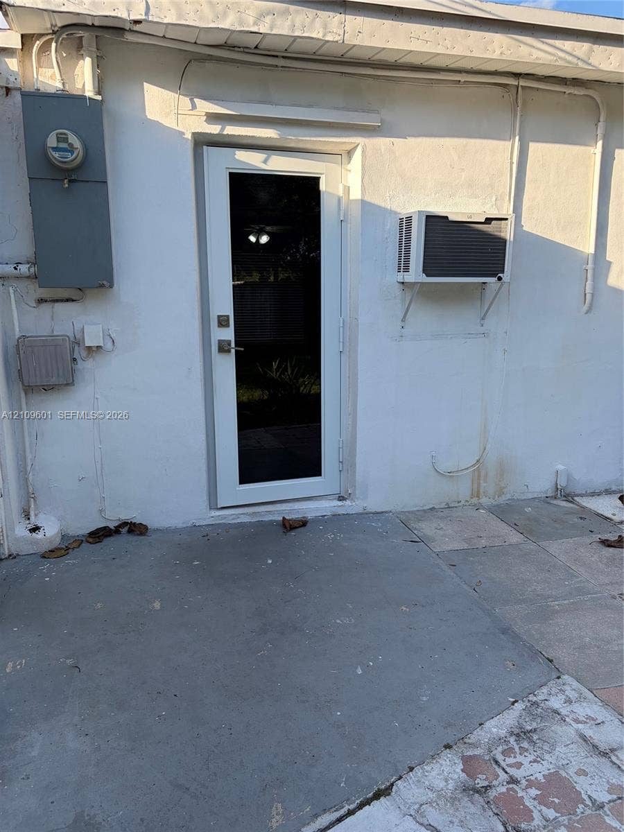 6320 Cleveland Street, Hollywood, Hollywood, FL 33024 Exterior entry featuring a glass-panel door, concrete patio surface, and a wall-mounted cooling unit