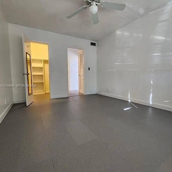 1851 NE 62nd Street, #610, Fort Lauderdale, FL 33308 Room featuring gray resilient flooring, built-in shelving, and a ceiling fan with light fixture