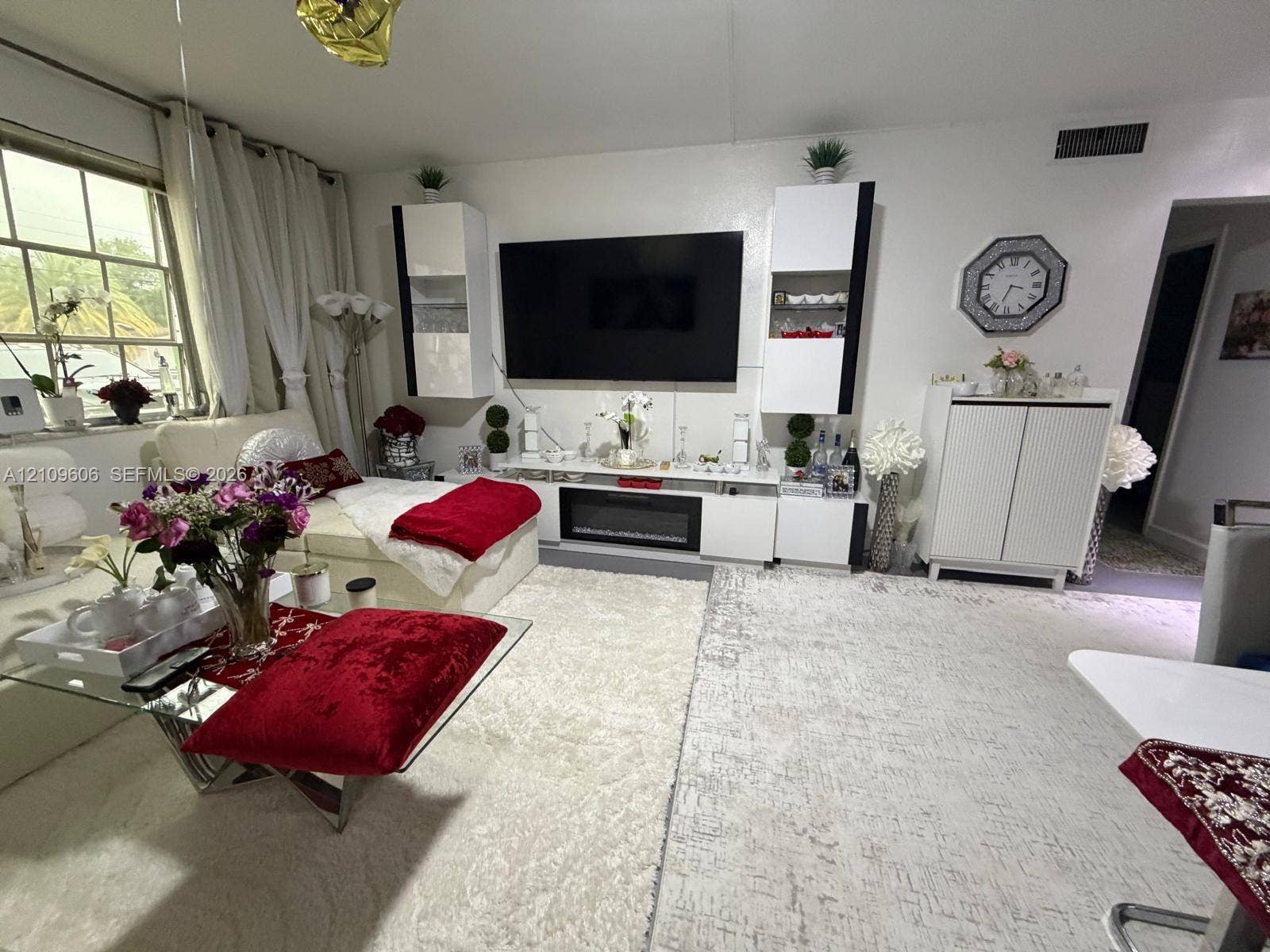 1851 NE 62nd Street, #610, Fort Lauderdale, FL 33308 Living area featuring built-in white media cabinetry, a centralized electric fireplace insert, and large windows with multi-pane glazing