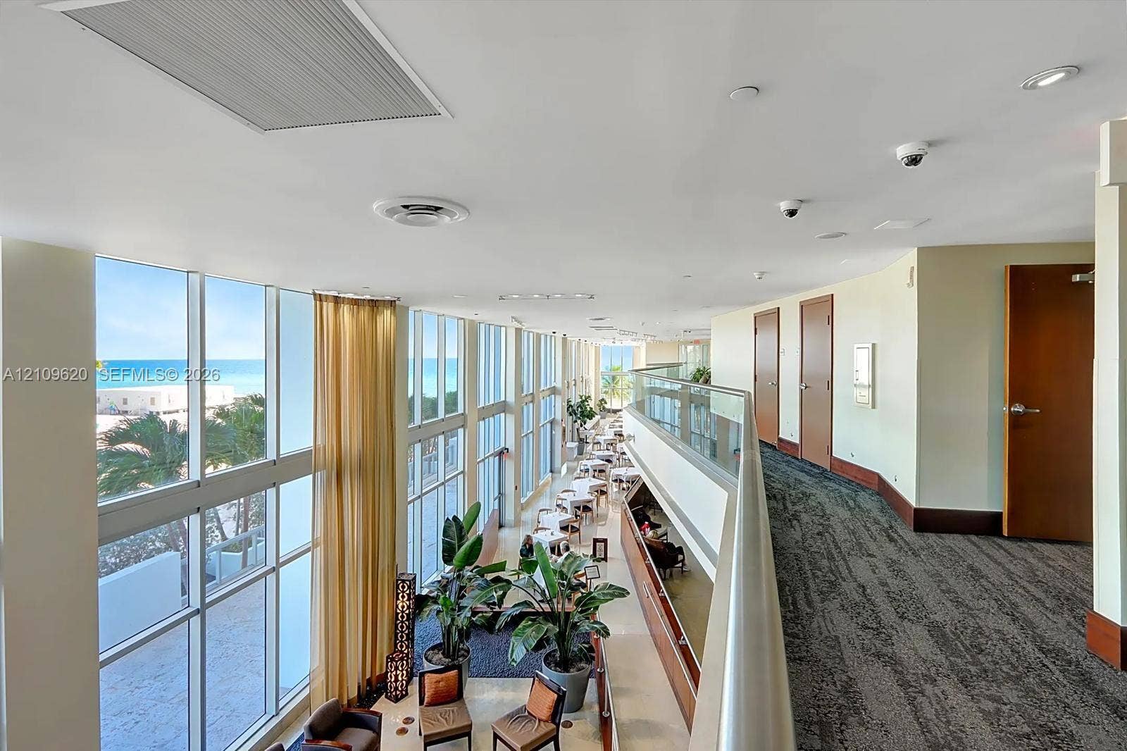 Floor-to-ceiling windows, glass paneled balcony railing, high ceilings, recessed lighting, and carpeted flooring