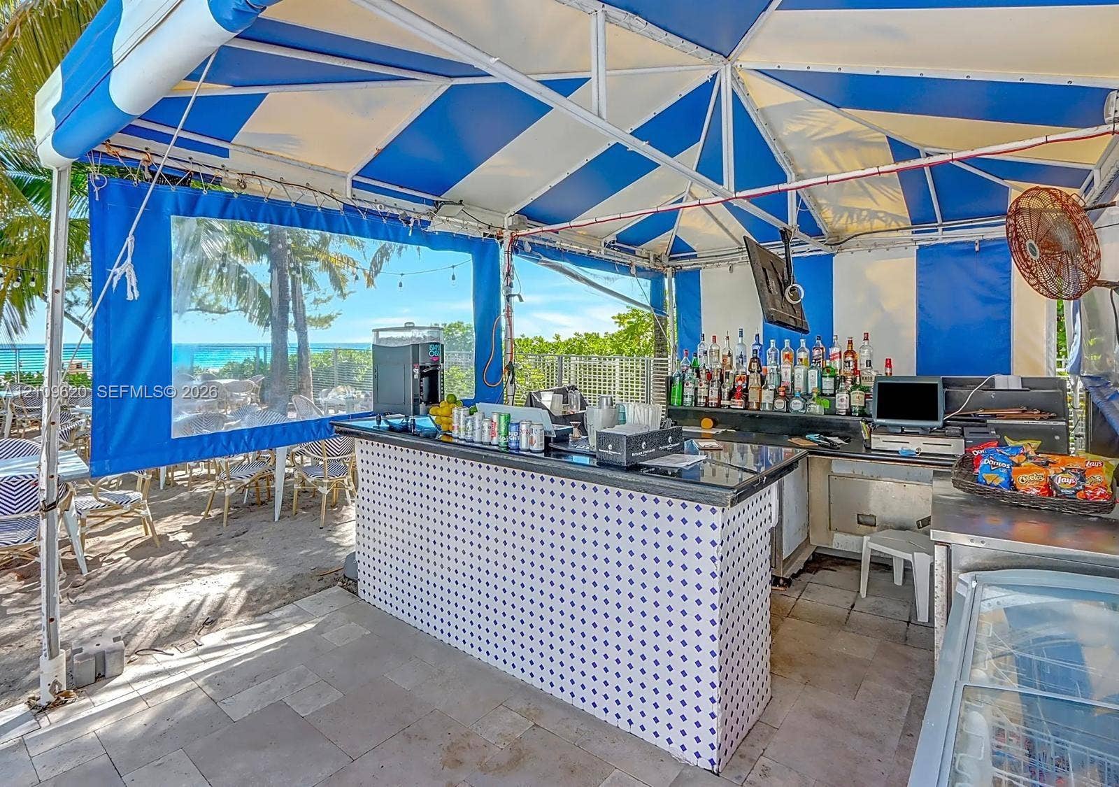 Outdoor bar area featuring a stone-tile patio, a custom tiled bar base, and a retractable overhead canopy structure