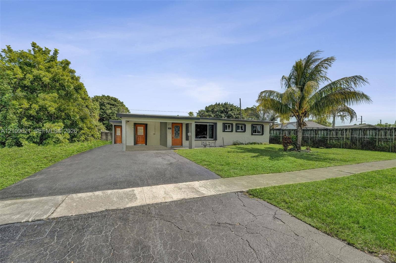 231 SW 64th Way, Pembroke Pines, FL 33023 Single-story exterior featuring a flat roofline, paved driveway, covered entryway, and mature palm tree