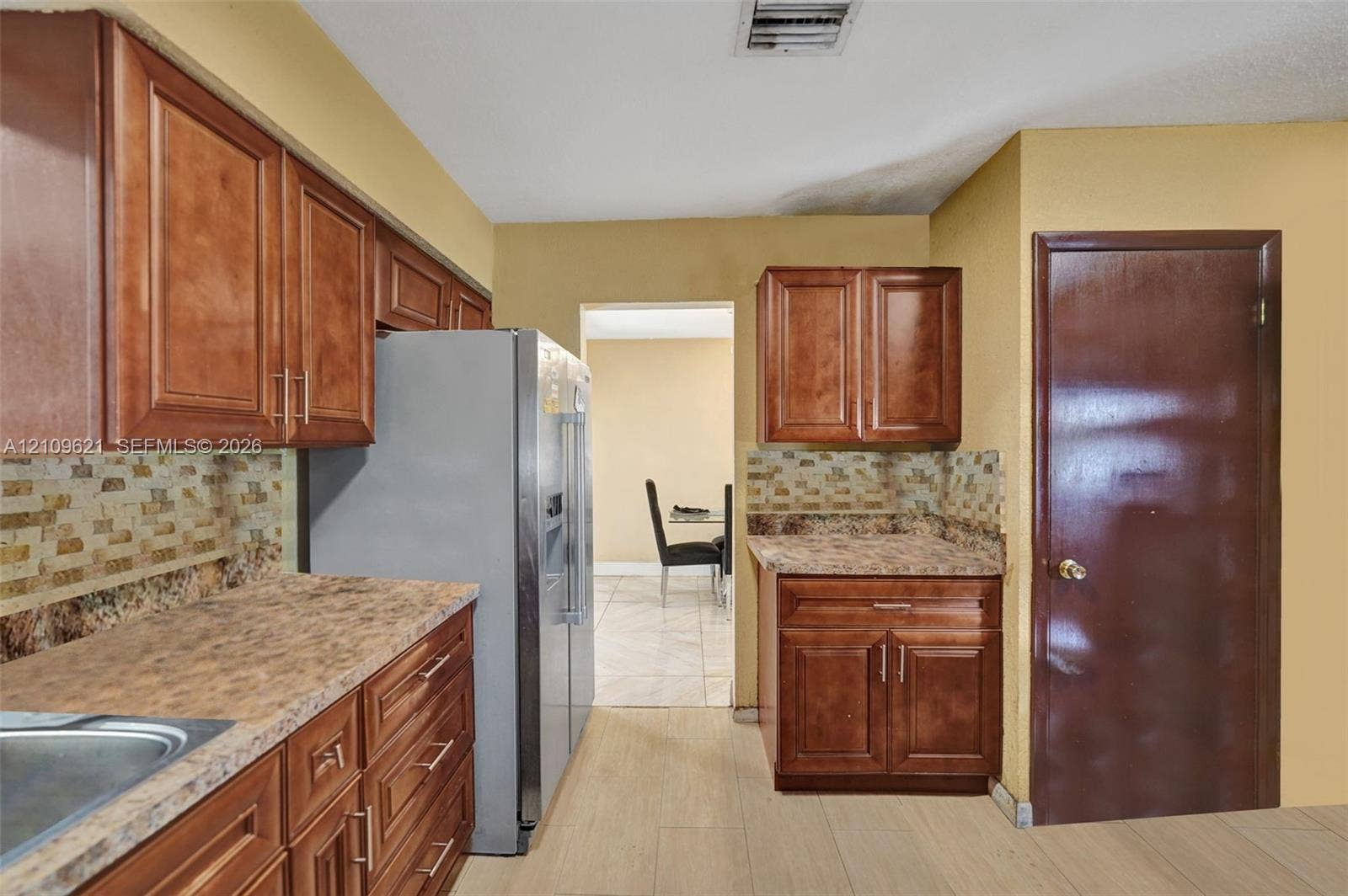 231 SW 64th Way, Pembroke Pines, FL 33023 Kitchen featuring wood-finish cabinetry, stone-patterned laminate countertops, and a textured tile backsplash