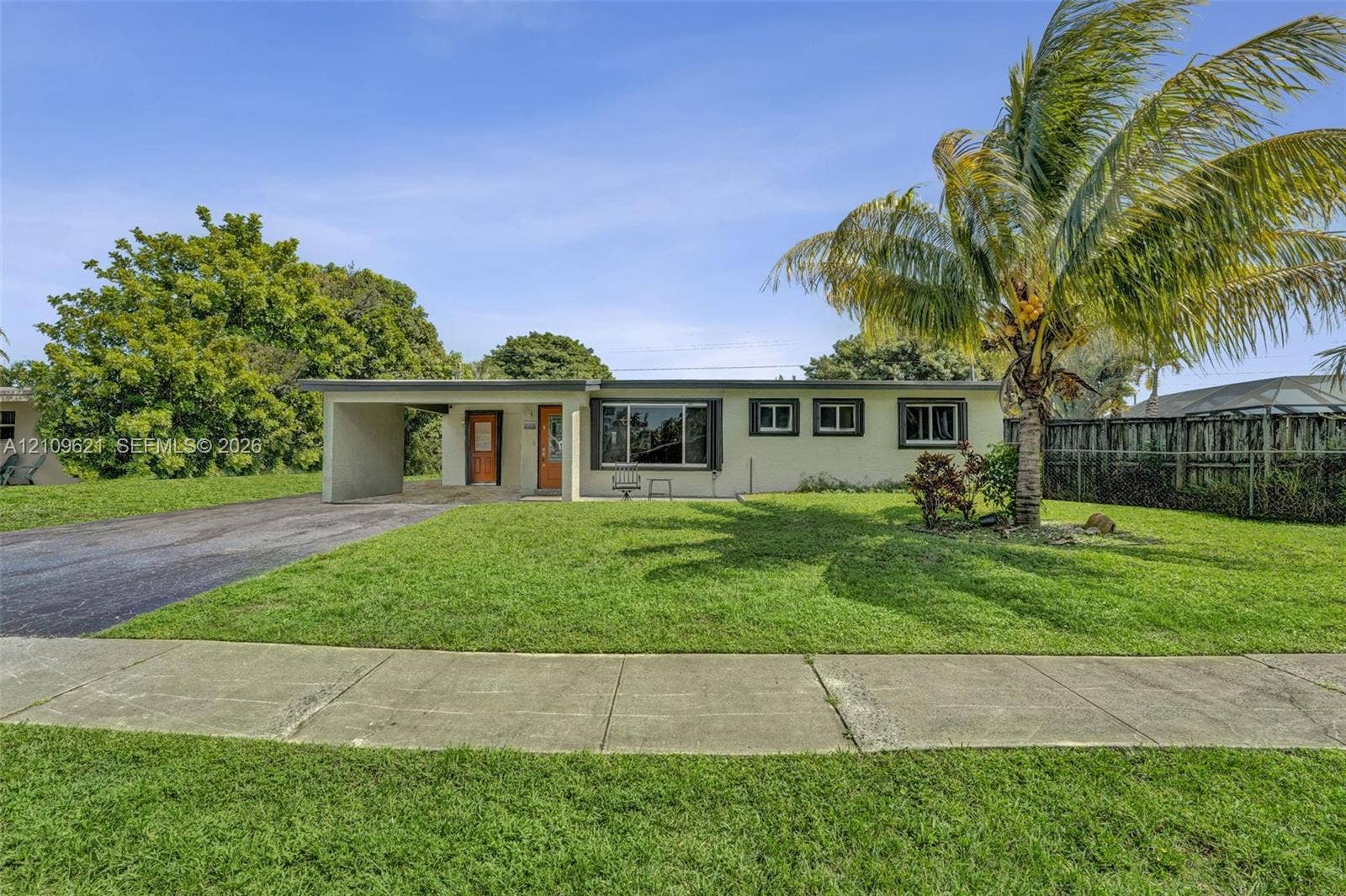 231 SW 64th Way, Pembroke Pines, FL 33023 Single-story exterior featuring a stucco facade, attached carport, asphalt driveway, and mature landscaping