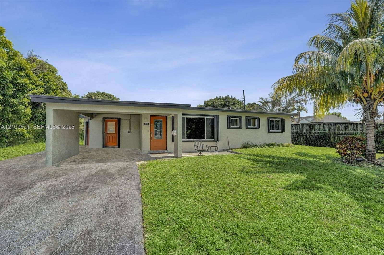 231 SW 64th Way, Pembroke Pines, FL 33023 Single-story exterior featuring a flat roofline, attached carport, concrete driveway, and front lawn with mature palm tree