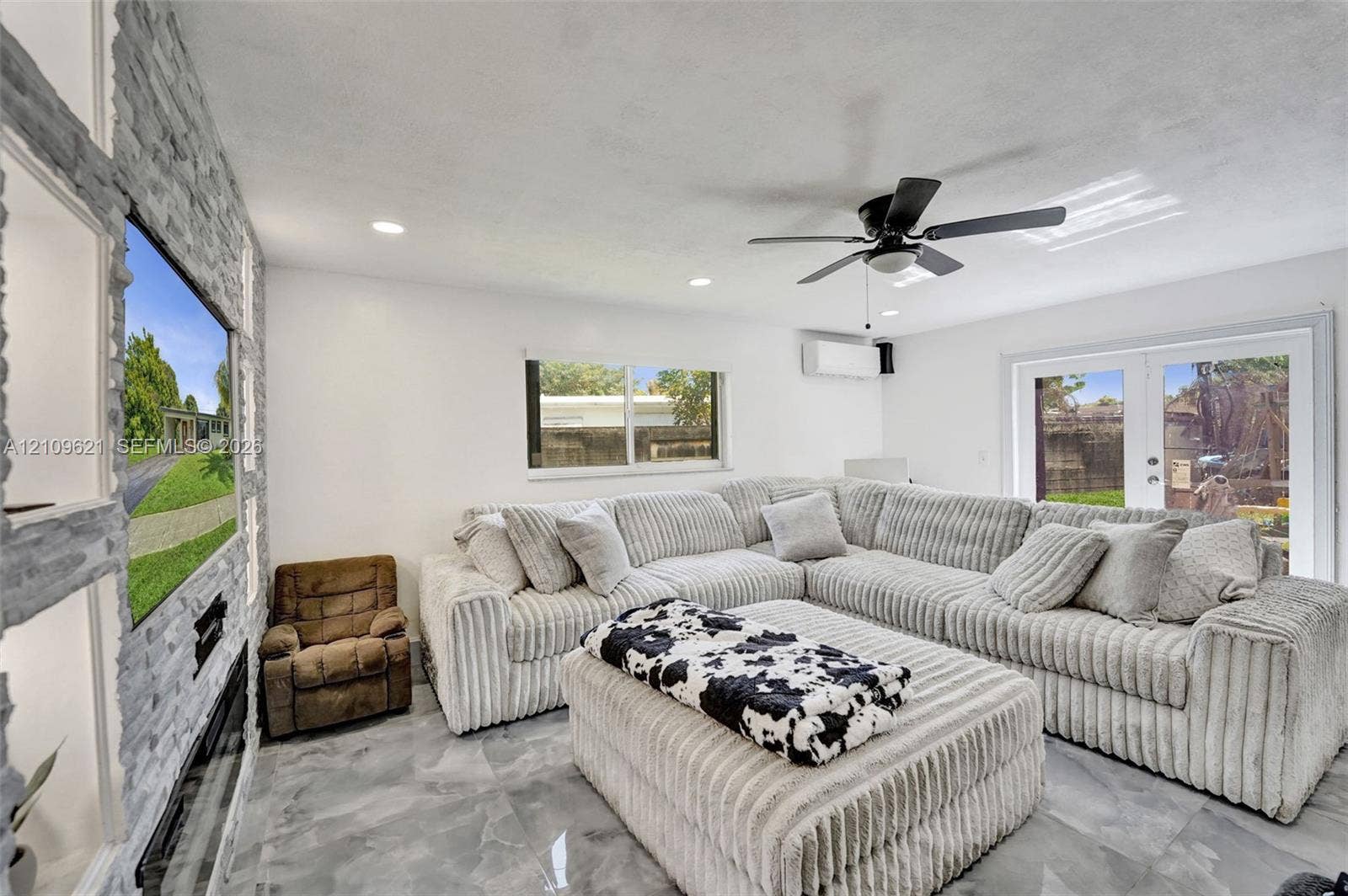 231 SW 64th Way, Pembroke Pines, FL 33023 Floor-to-ceiling stone-textured accent wall with integrated shelving, built-in electric fireplace, recessed lighting, ceiling fan, and large-format tile flooring