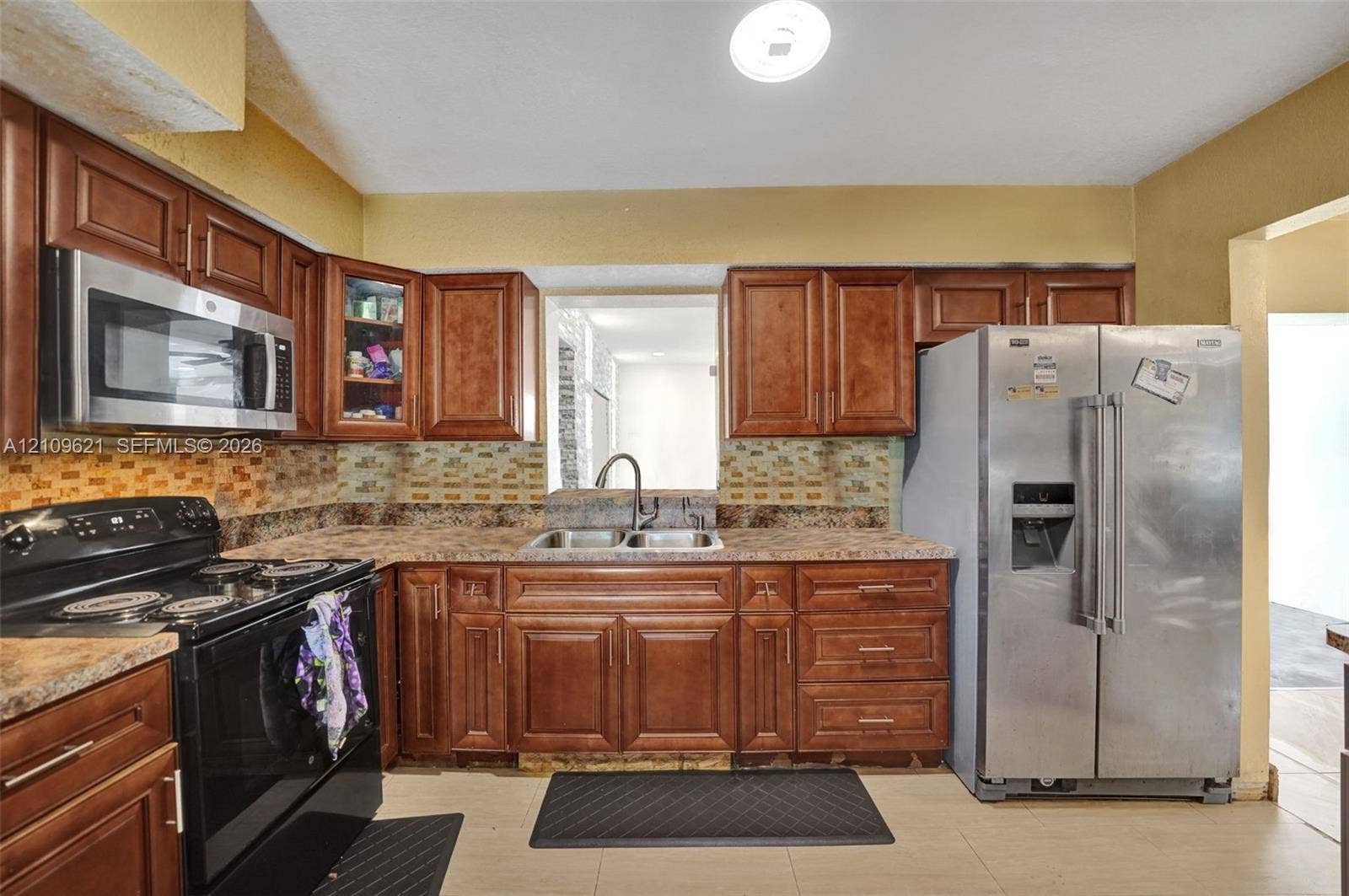 231 SW 64th Way, Pembroke Pines, FL 33023 Kitchen featuring stained-wood cabinetry, stone-finish countertops, stainless steel appliances, a mosaic tile backsplash, and a dual-basin sink with a gooseneck faucet