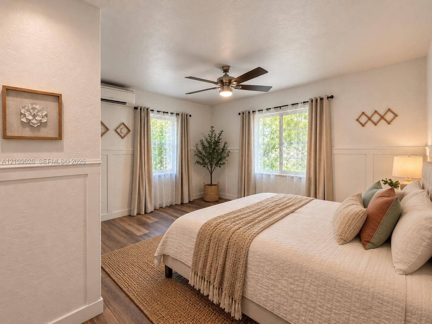 Room featuring wood-finish flooring, half-wall wainscoting, a ceiling fan with integrated lighting, and dual windows