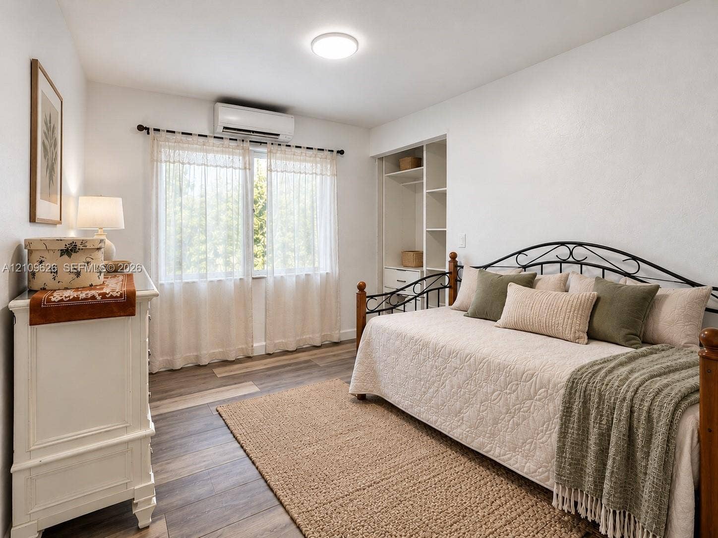 Wood-finish flooring, wall-mounted climate control unit, built-in shelving, and flush-mount ceiling lighting