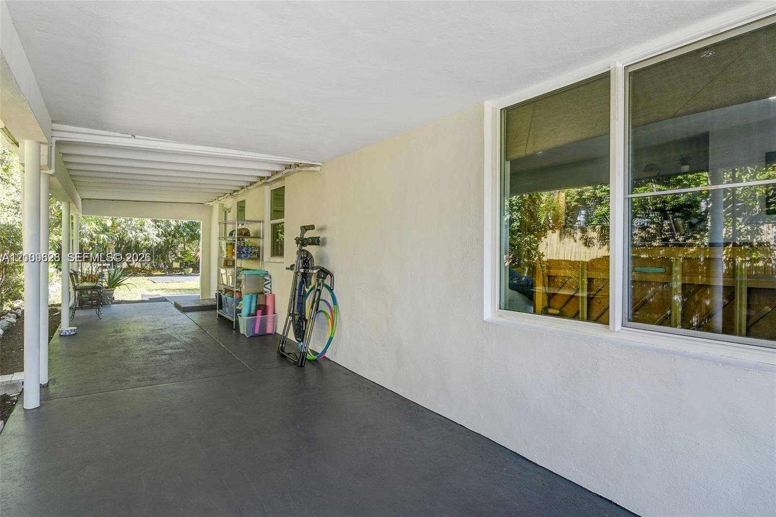 Covered exterior space featuring a concrete floor, support columns, and large multi-pane windows